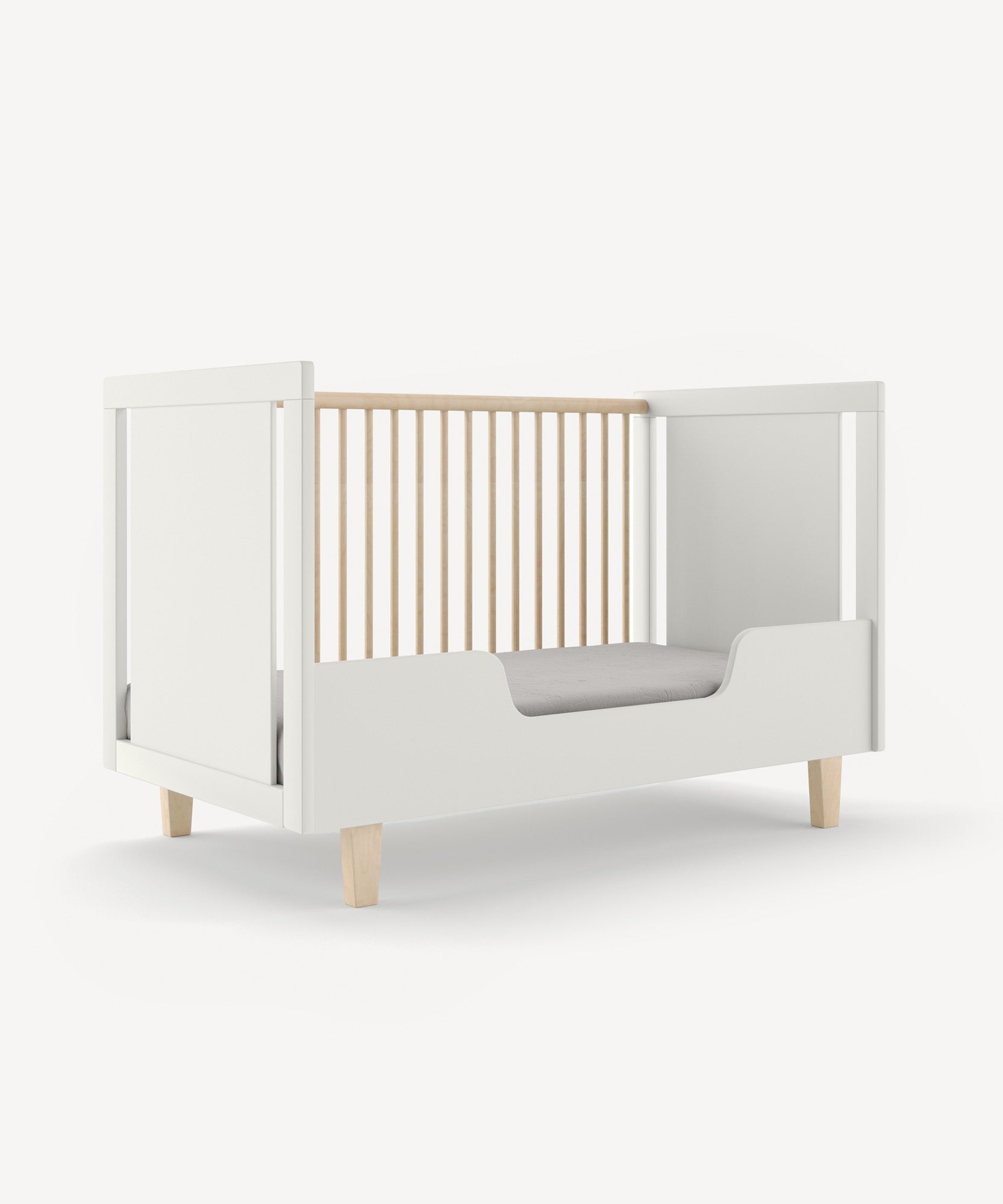 The Rhea Toddler Bed Conversion Kit features a white bed with wooden slatted sides and light wooden legs on a plain background.