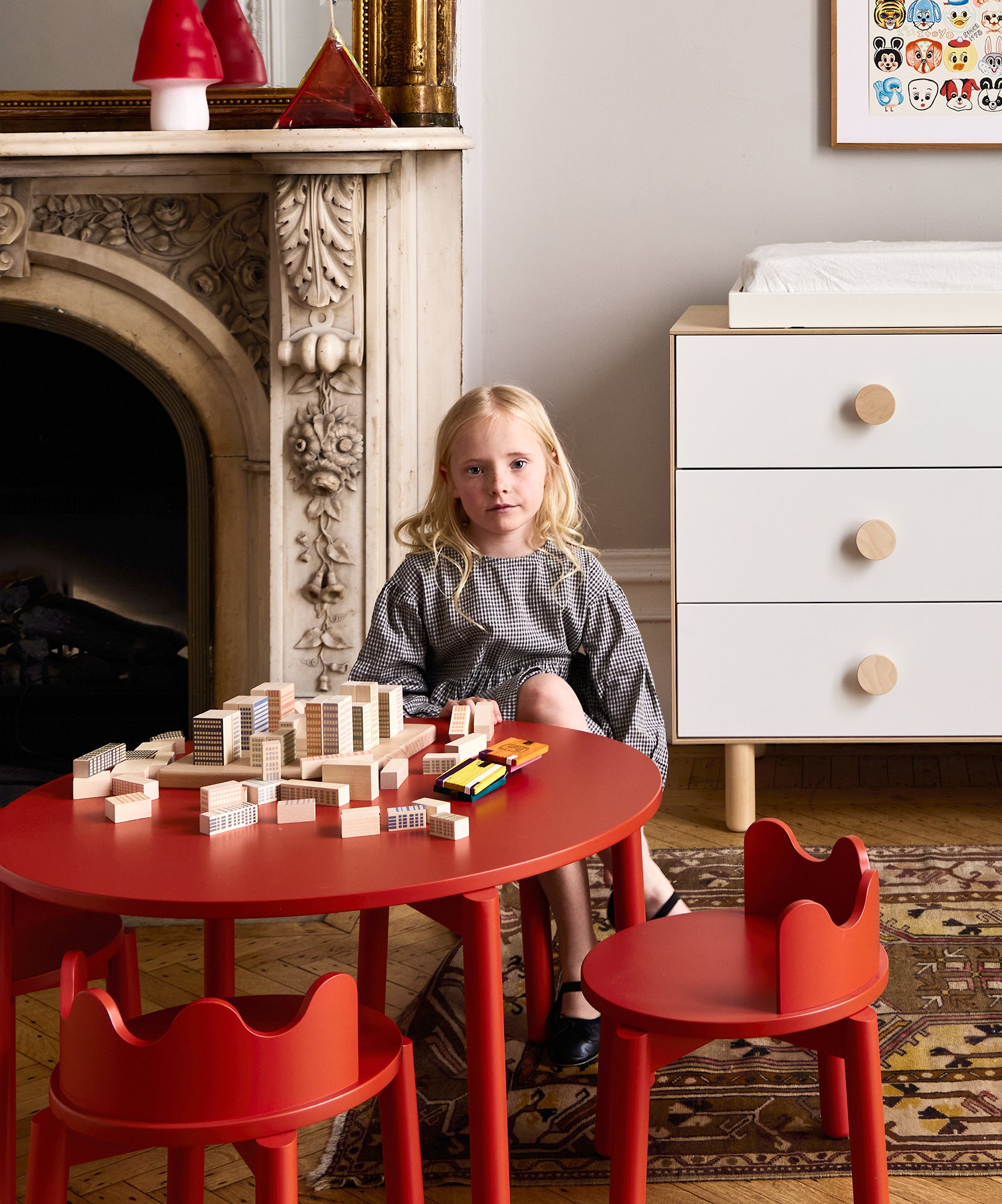 A young girl sits at a Moss Table with building blocks in a cozy, stylish room featuring modern and classic decor.