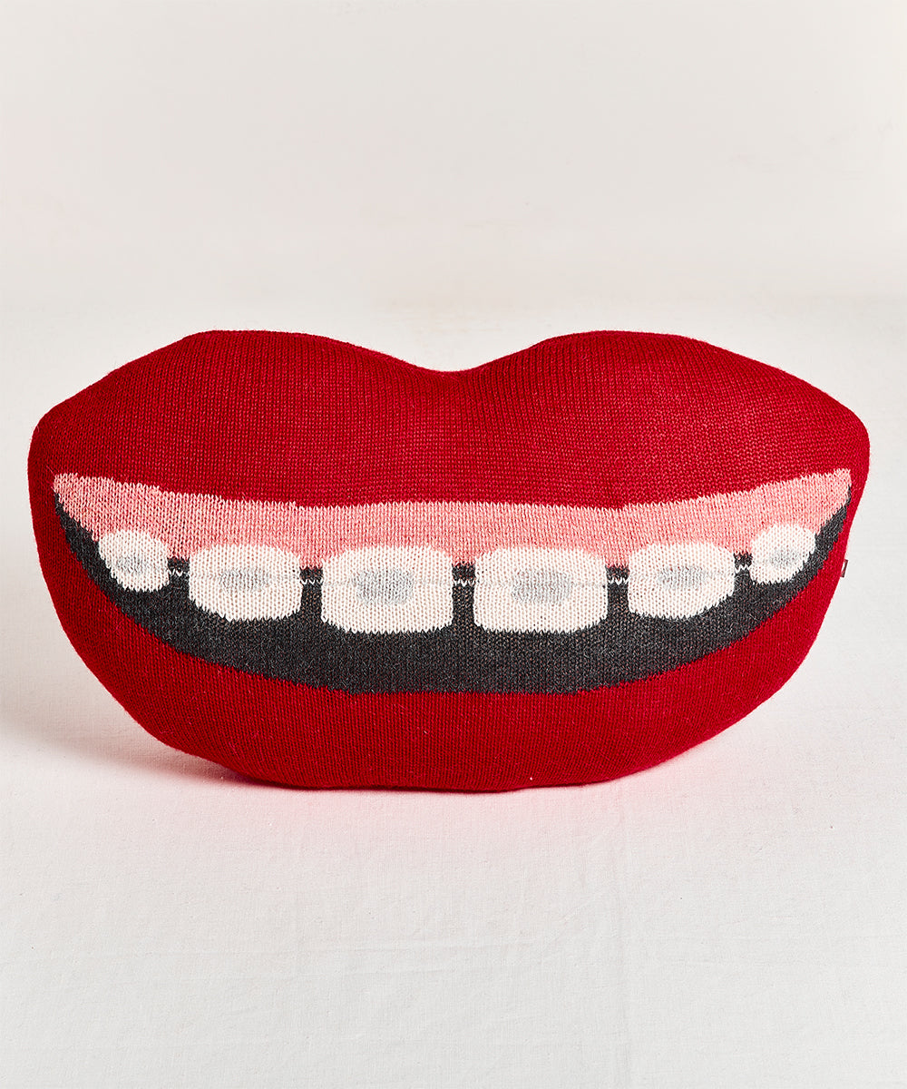 Red knitted Mouth Pillow - Braces; lip-shaped with a wide smile showing teeth against a plain background.