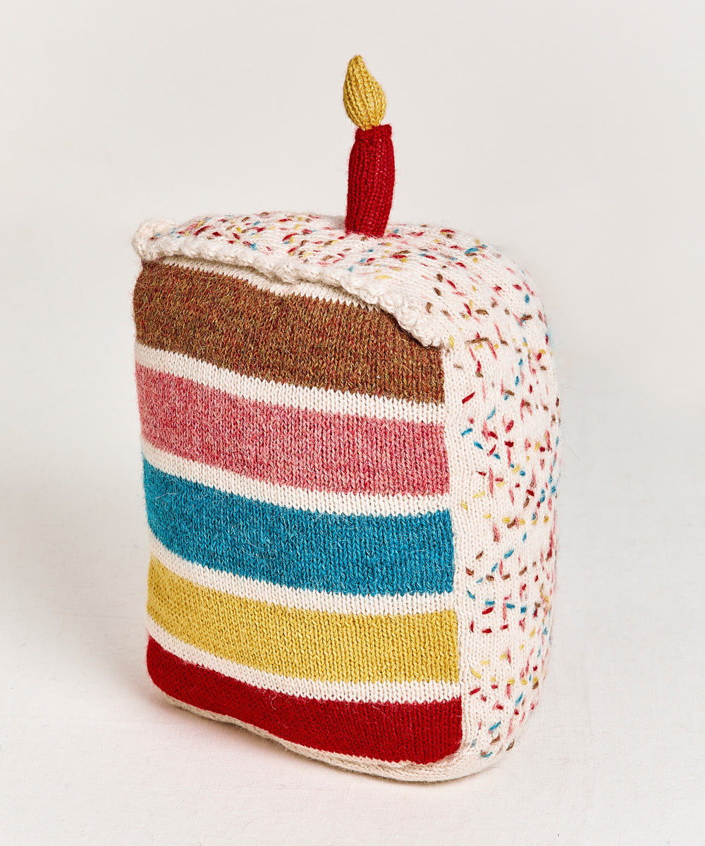 Birthday Cake Pillow featuring vibrant knitted layers and a candle on top.