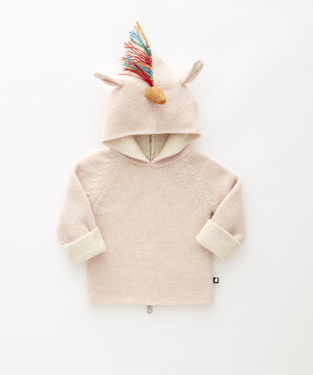 Unicorn Hoodie in light pink knit with rolled sleeves, animal ears, and a colorful yarn mane on the hood, laid flat on white.